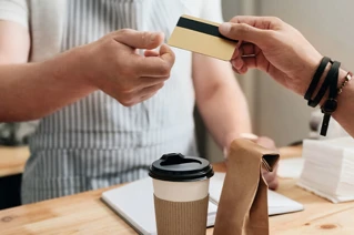A person handing over a loyalty card to the cashier
